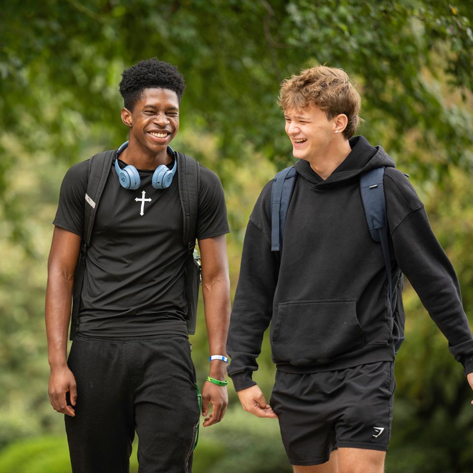 Two students walk together smiling