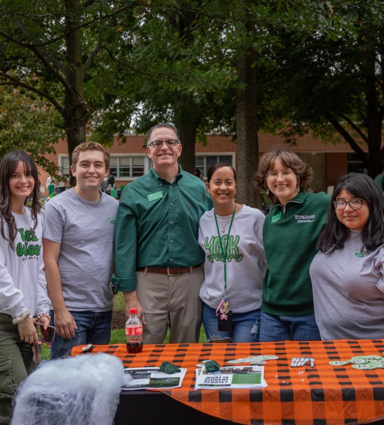 President Burns poses for a group photo with five York College students working a table at the Involvement Fair.