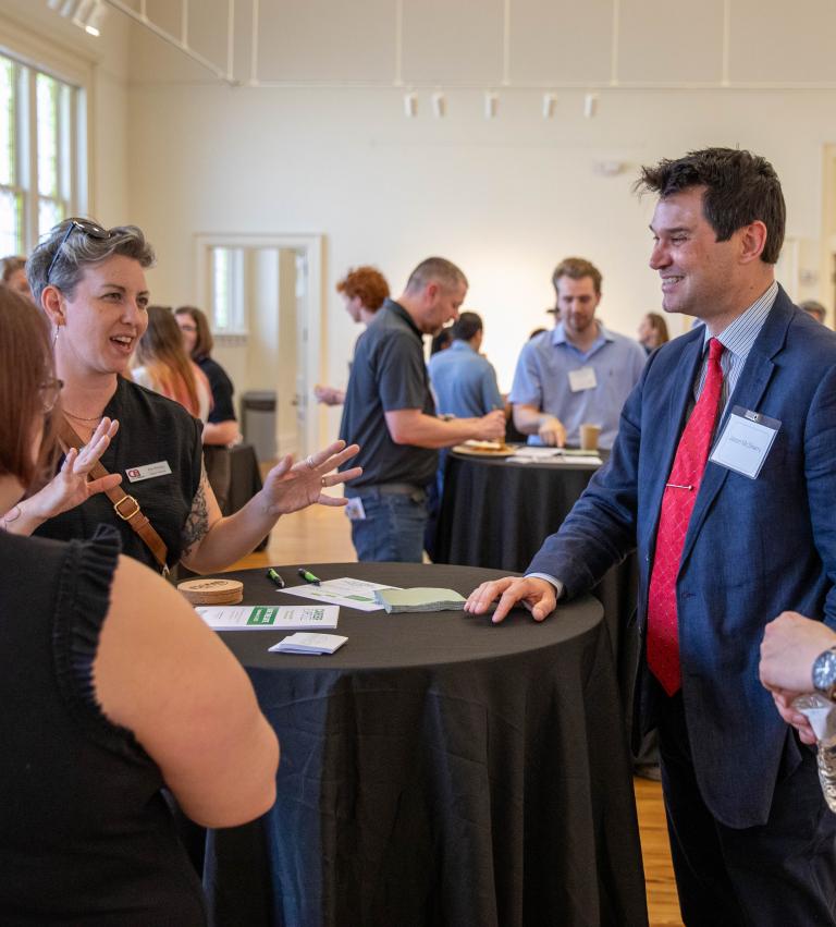 Attendees engage in animated conversation around a high-top table during a GCCI live networking event held in a bright, open room with natural light.