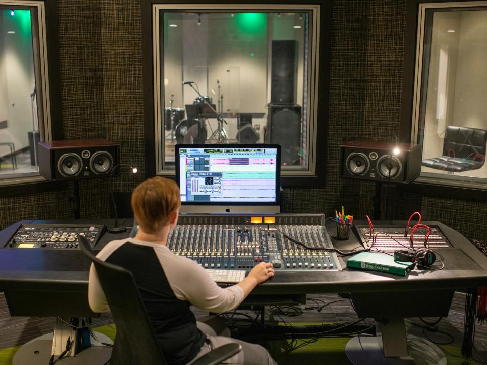 A student works at a sound board in the recording studio.