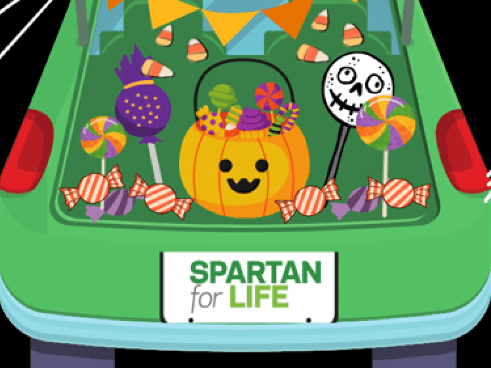 An illustrated graphic shows a car trunk full of jack-o-lanterns and candy. The license plate reads "Spartan for Life." 