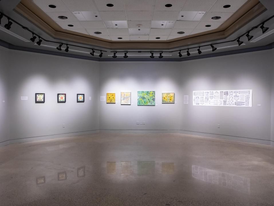 Artwork displayed on gray walls in gallery on main campus.