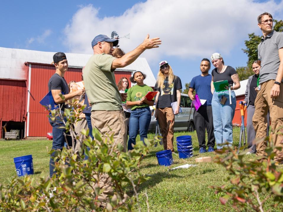 Horticulture class outdoors with instructor speaking to students near a red barn.