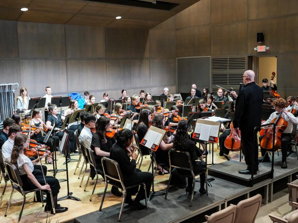 A large group of young musicians playing instraments in a theater