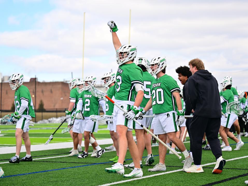 A group of Men's Lacrosse players on a field in their gear.