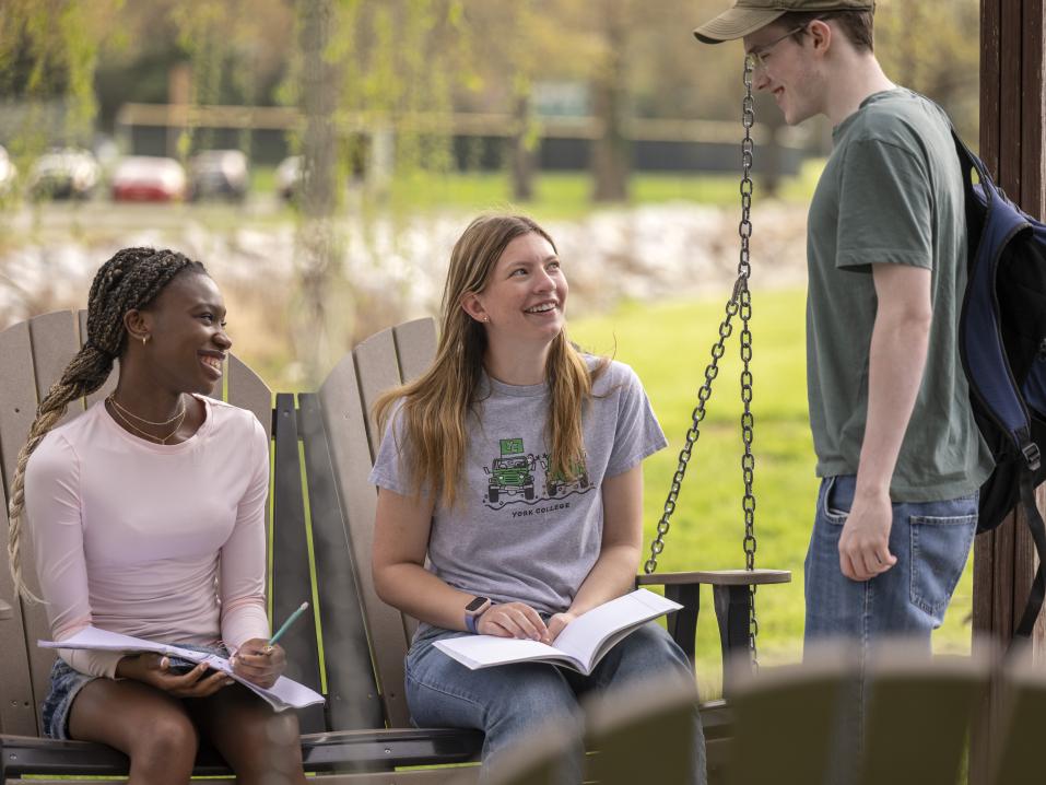 Three students sitting together near the creek.