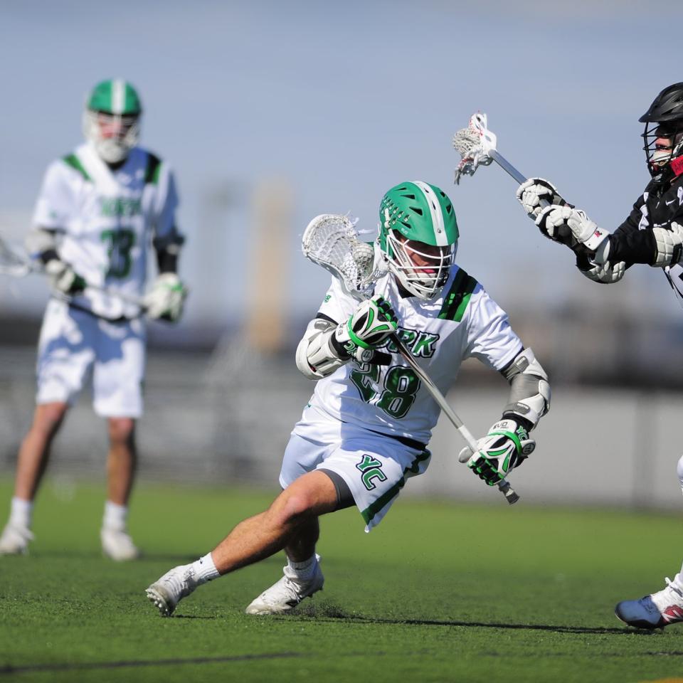 York lacrosse player runs with the ball as opposing player attacks