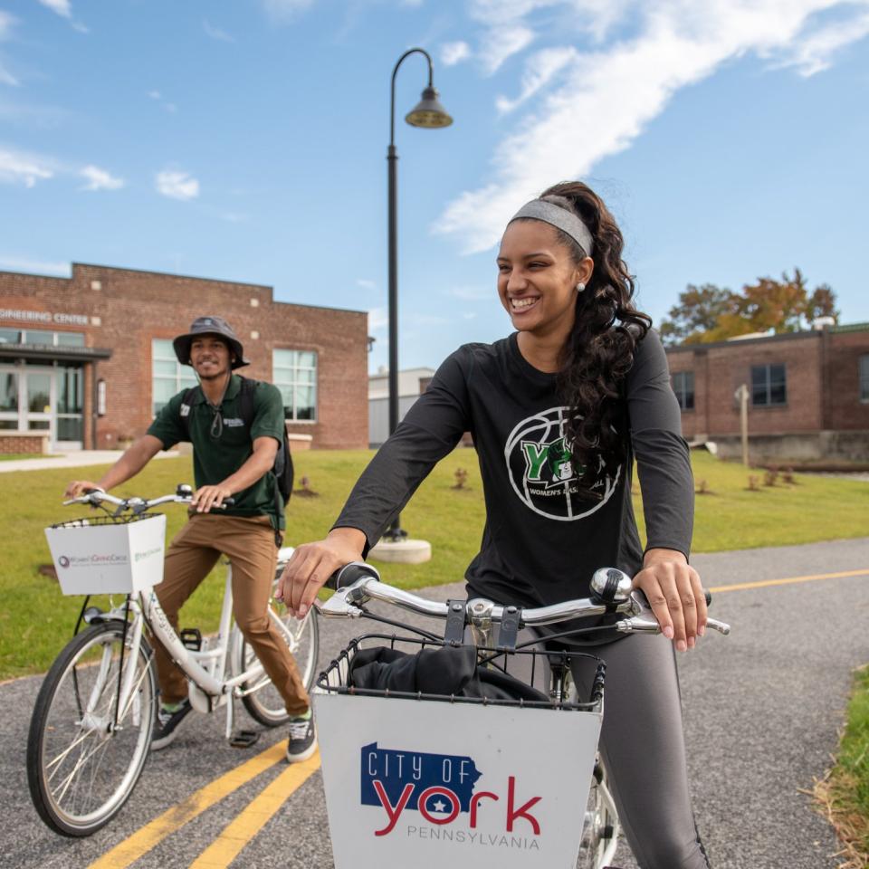 Two students smiling enjoying a bike ride on a greenway