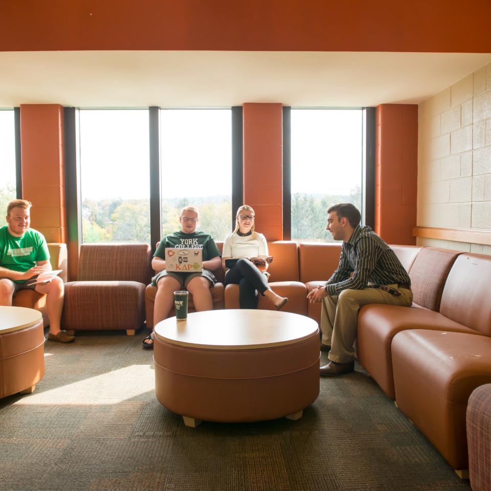 Four students sit together in common space in residence hall