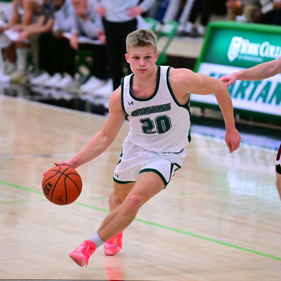 A Men's Basketball player dribbles the ball.