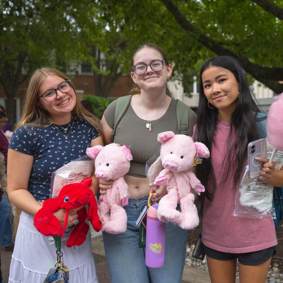 Three student pose with stuffed animals.