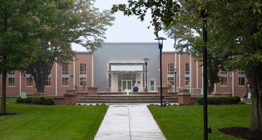 An outdoor view of the library, with the fountain in front at the center of the campus quad.