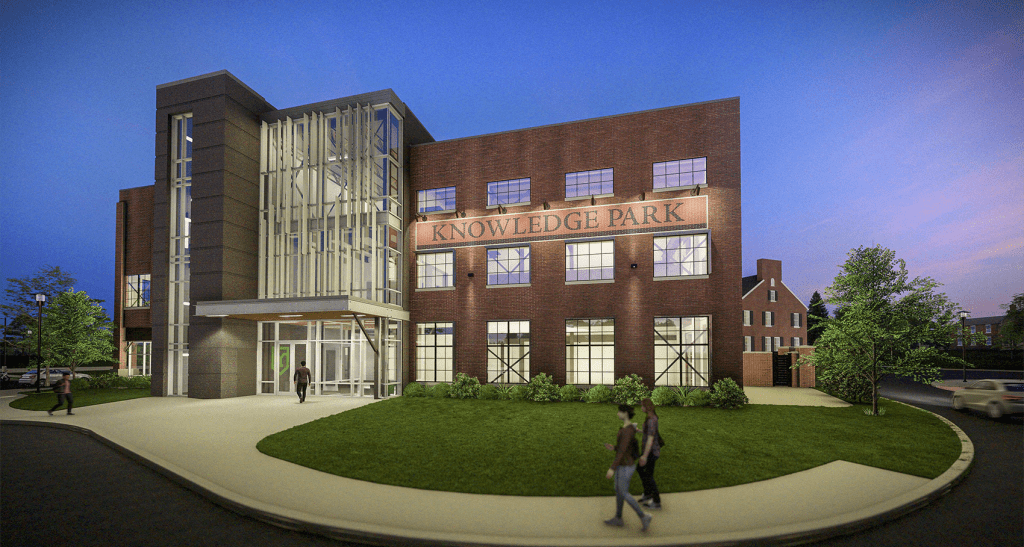 An artist's rendering shows a nighttime exterior view of the Knowledge Park building, featuring brickwork and a section of three-story glass windows.