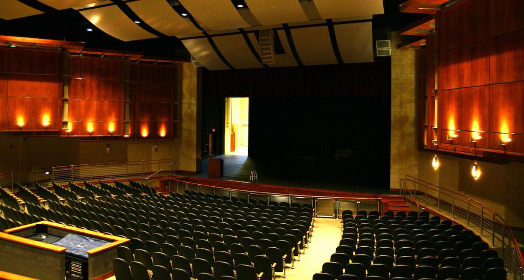 The interior of the Waldner Performing Arts Center Theater shows a stage in front of dozens of rows of seating.