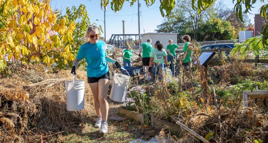 A student holds two buckets while cleaning out a garden