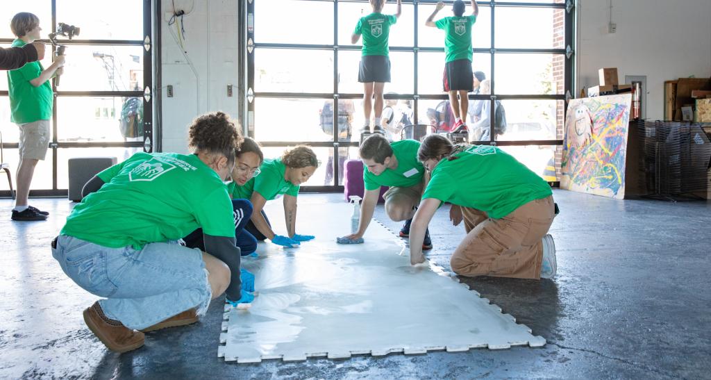 Students in Green Spartan Serve t-shirts clean floors and walls of Keystone Kid Space