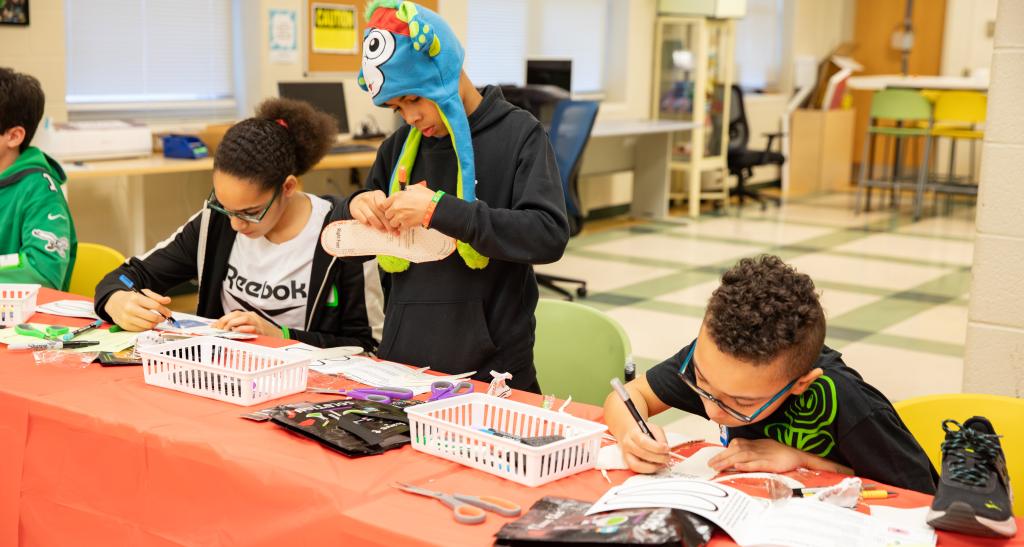 A group of students work at a desk on a craft or project