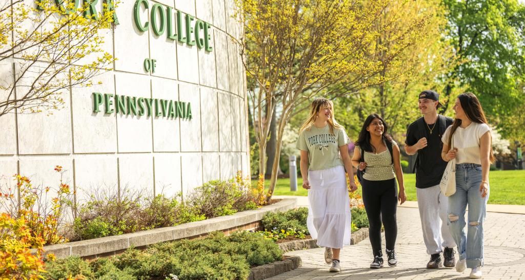 A group of YCP students walking in front of a York College sign.