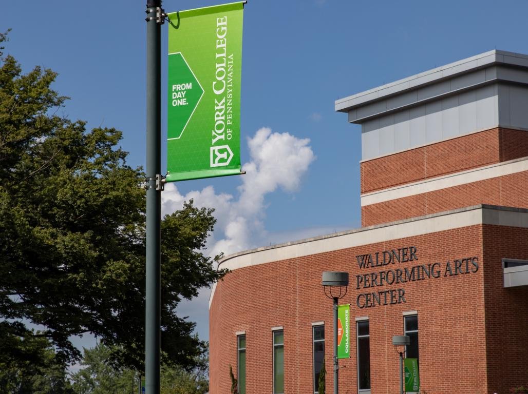 An Exterior photo of Waldner Performing Arts Center with a YCP flag in the center.