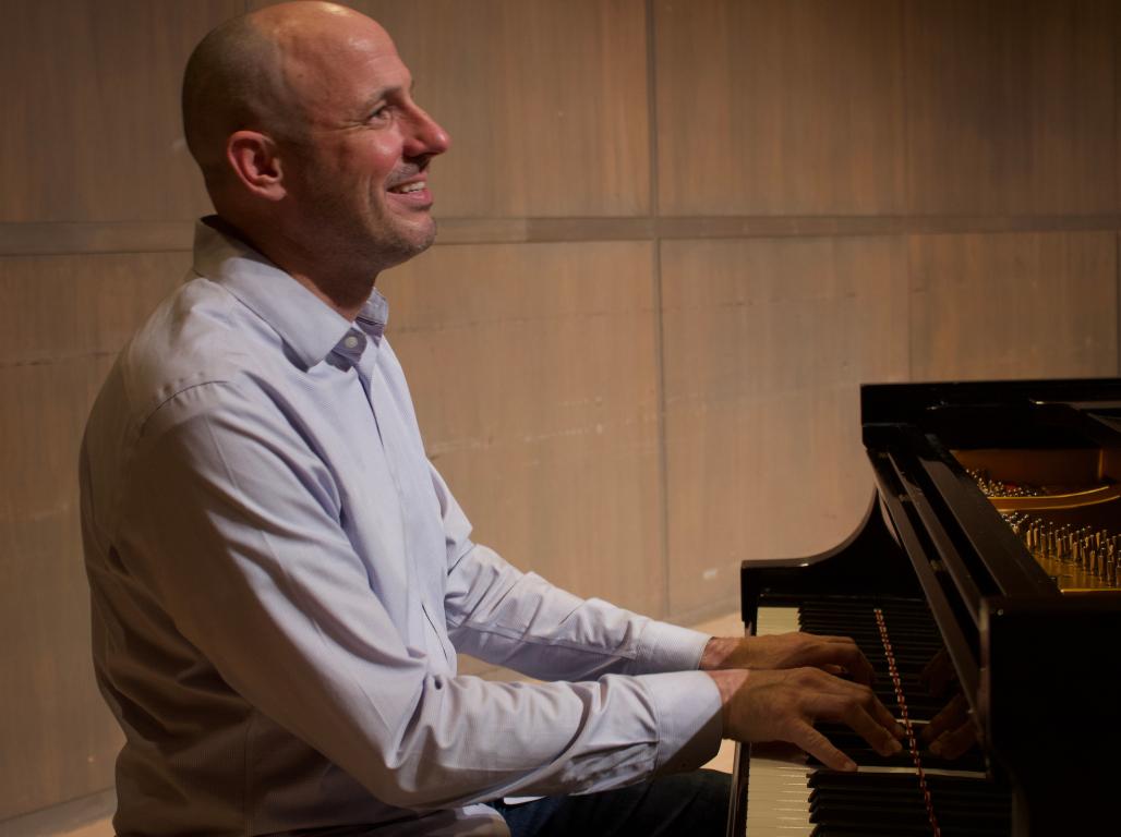 Professor Ken Osowski plays the piano on stage at York College.
