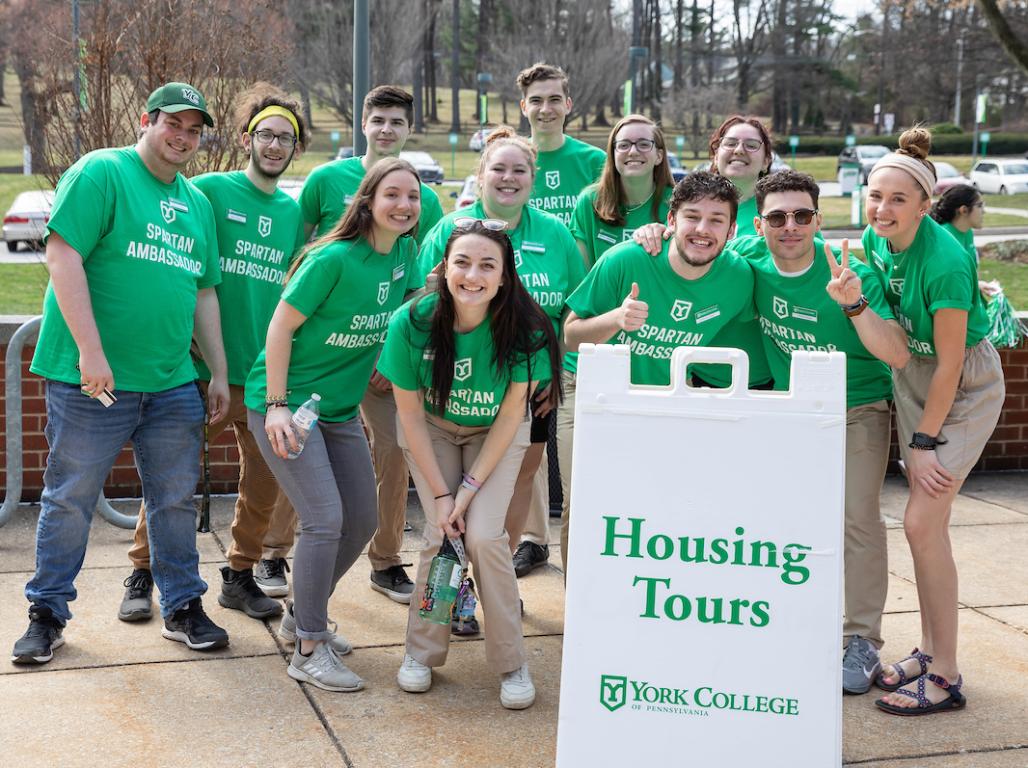 A group of Spartan Ambassadors in front of a Housing Tours sign.