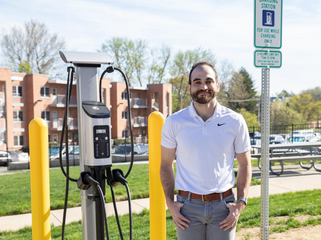 Daniel Kreiman stands next to an electric vehicle charging station on campus.