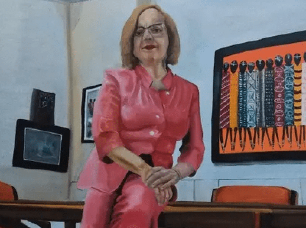 A painting portrays President Pamela Gunter-Smith in a red pantsuit, leaning against an office desk.