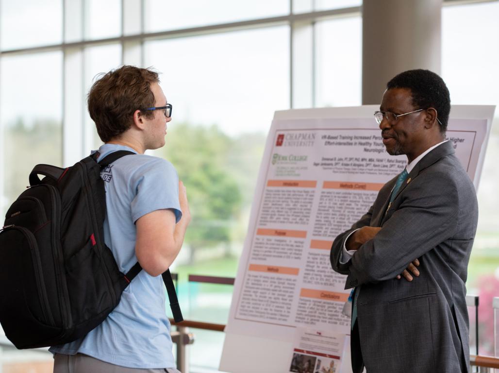 A faculty member is engaging in conversation with a student during the faculty showcase