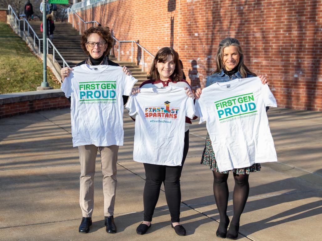 Dr. Kay McAdams, Madison Sweitzer, and Professor Andrienne Brenner hold up "First Gen Proud" t-shirts