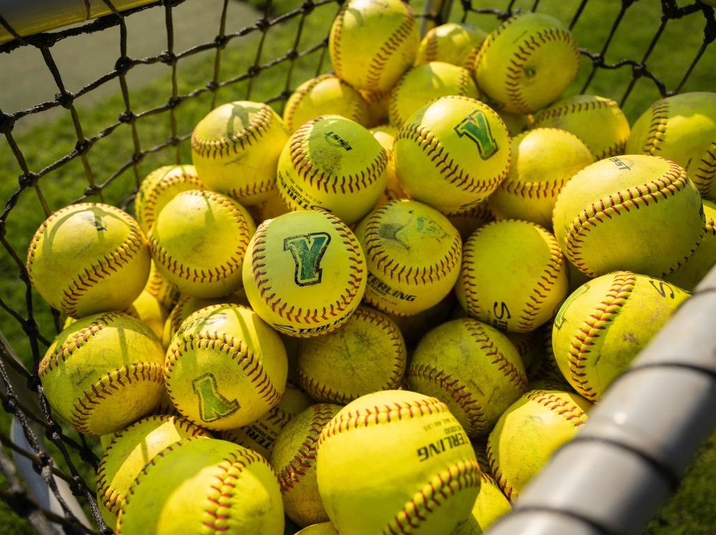 A basket of softballs together with the Y logo on them.