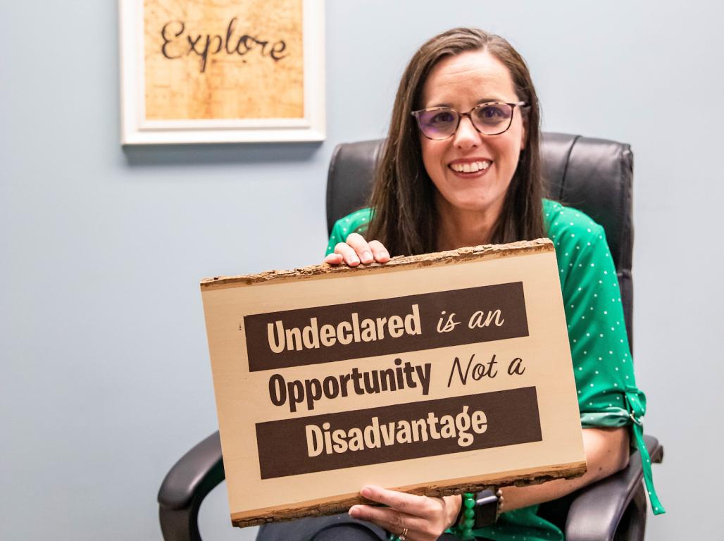 Stephanie Perago smiles at the camera while holding a sign that reads "Undeclared is an opportunity, not a disadvantage."