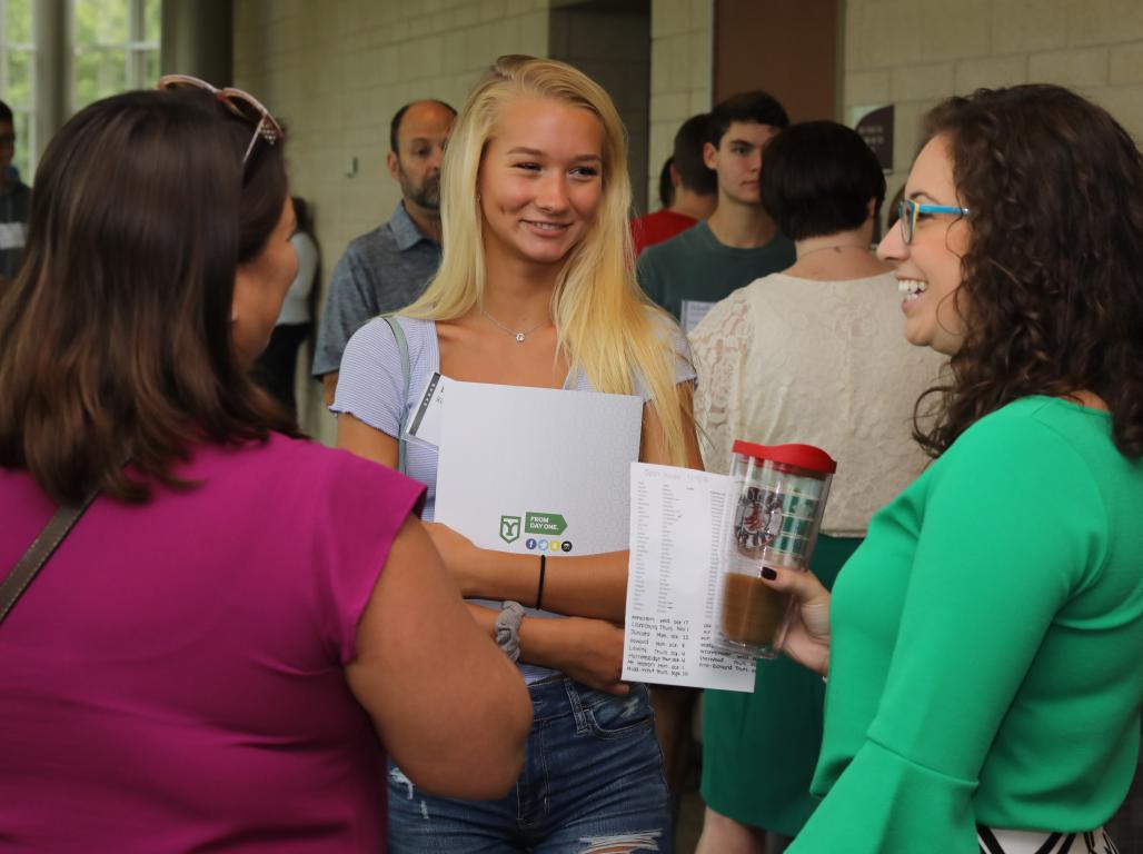 Prospective student and their parent talking to an admission counselor during an open house