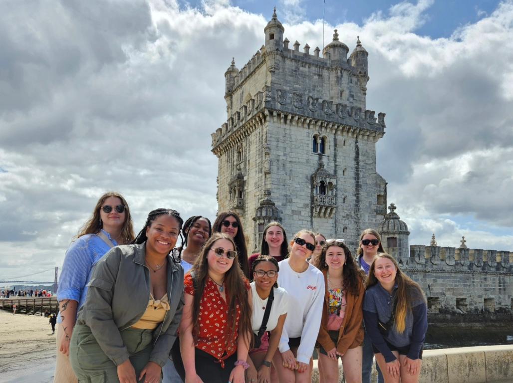 A group of YCP students in Portugal in front of a massive stone building.