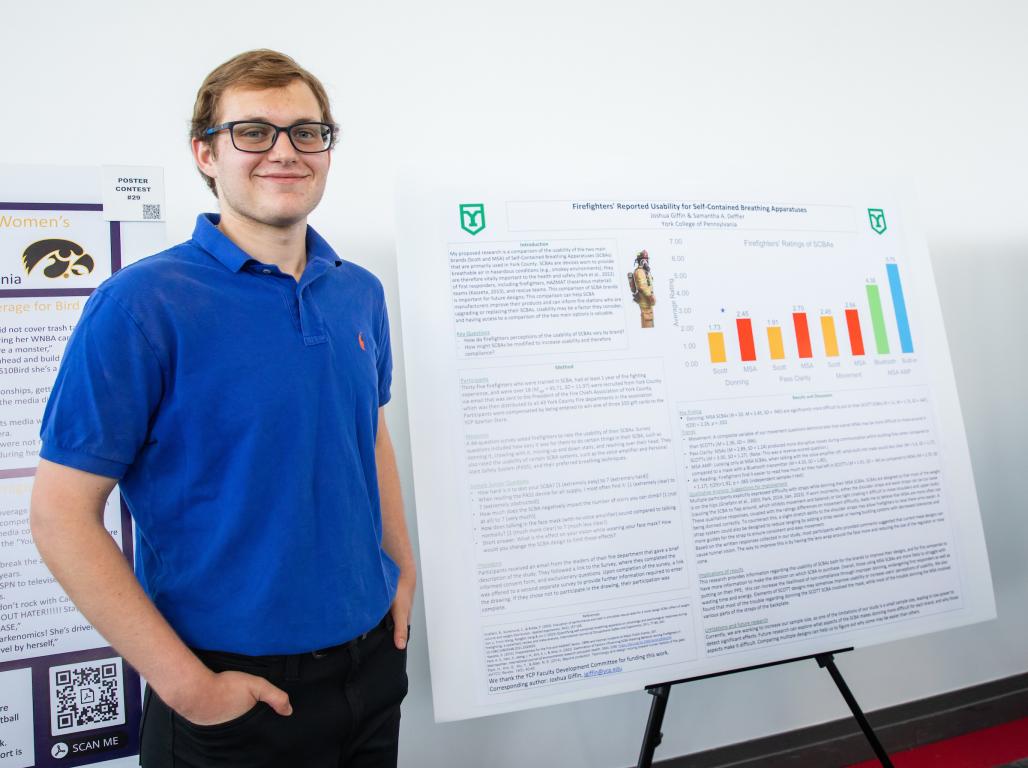 Josh Giffin next to his research poster at the research showcase.
