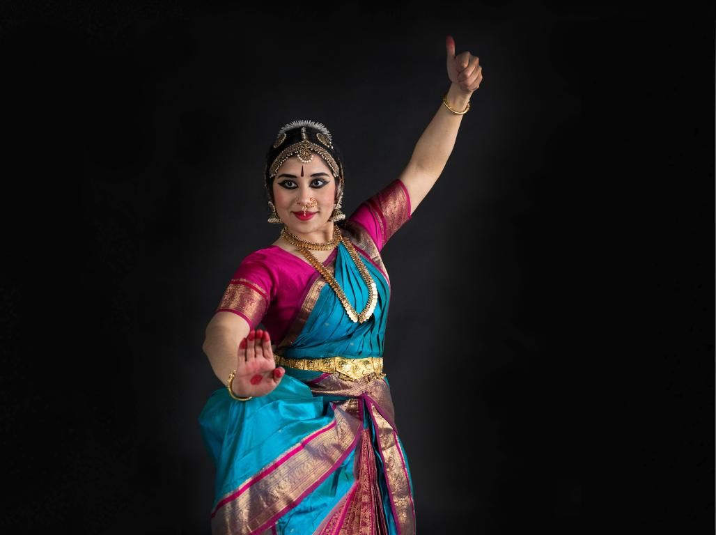 Professor Madhavi Reddi wears a traditional Indian performance costume while dancing in a studio.