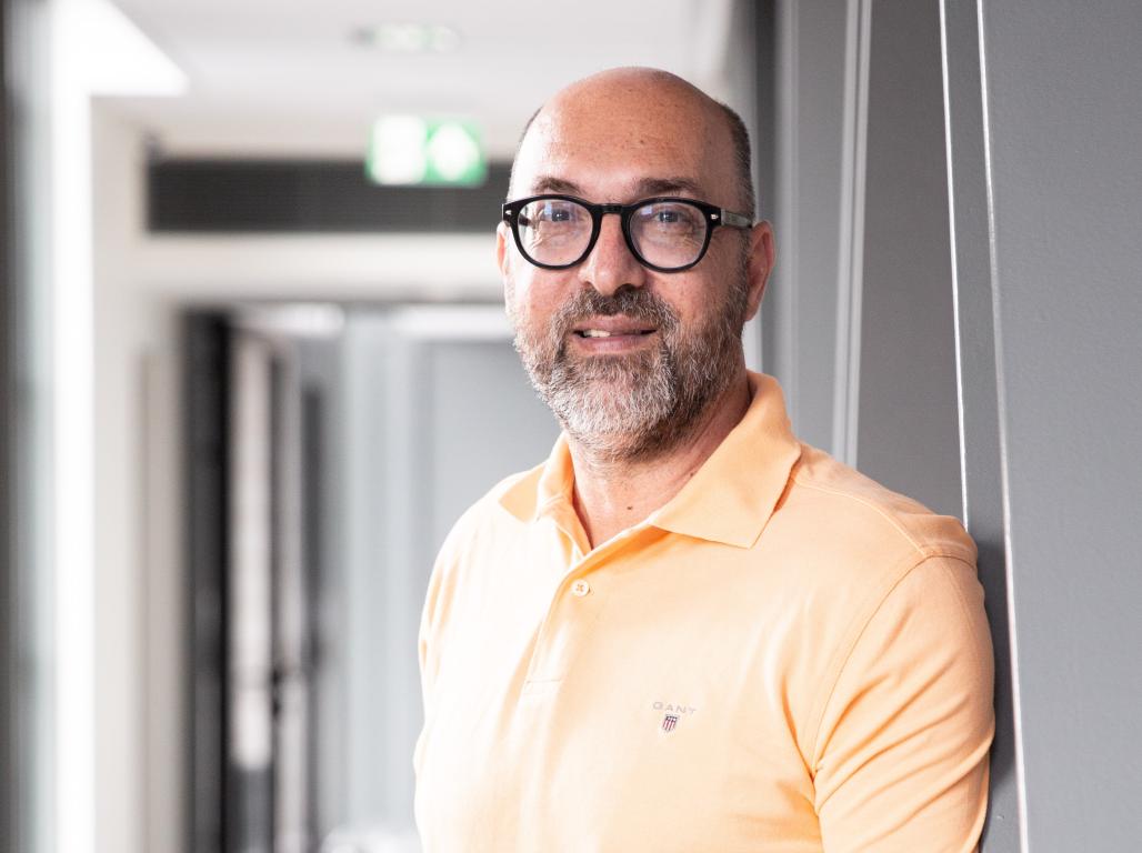 A portrait of Konstantinos Petridis, standing in a hallway of a modern building.