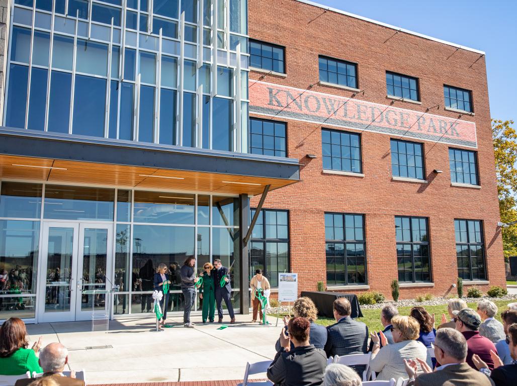 Five representatives of York College, the Knowledge Park, and tenants cut a large ribbon with large ceremonial scissors outside the Knowledge Park front doors.