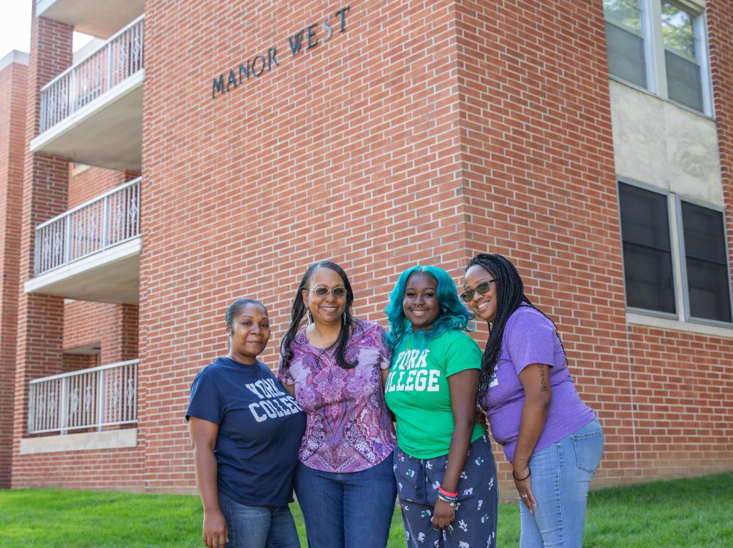 Sheila Cason-Gregory ’84 and granddaughter Aniya Gregory, with two additional family members, standing outside Manor Hall West. 