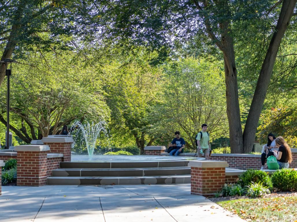 A view of the fountain on the YCP campus with students sitting nearby