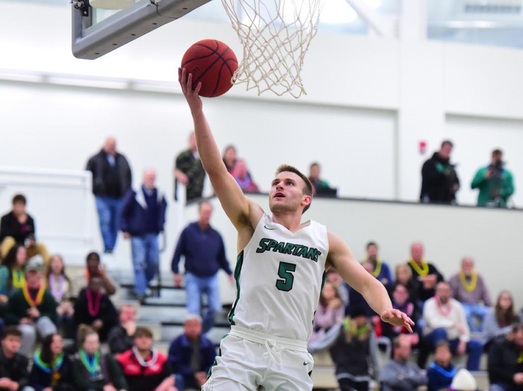 Jared Wagner can been seen holding a basketball in the air with the hoop right above his head