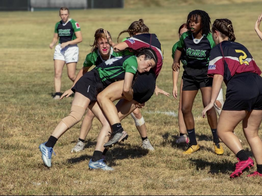 Women's Rugby players in action on the field.