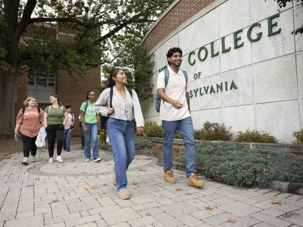 A group of students walks in front of the York College of Pennsylvania sign