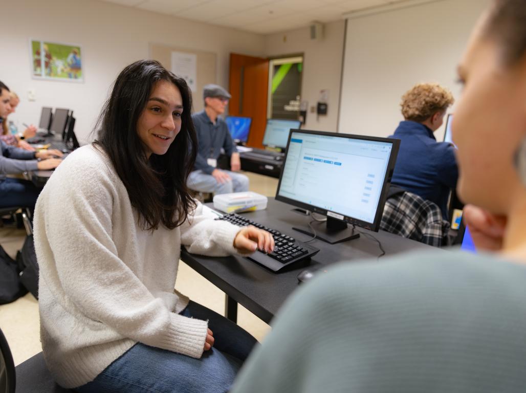 Victoria Jolakian sits at a computer talking to a woman off camera