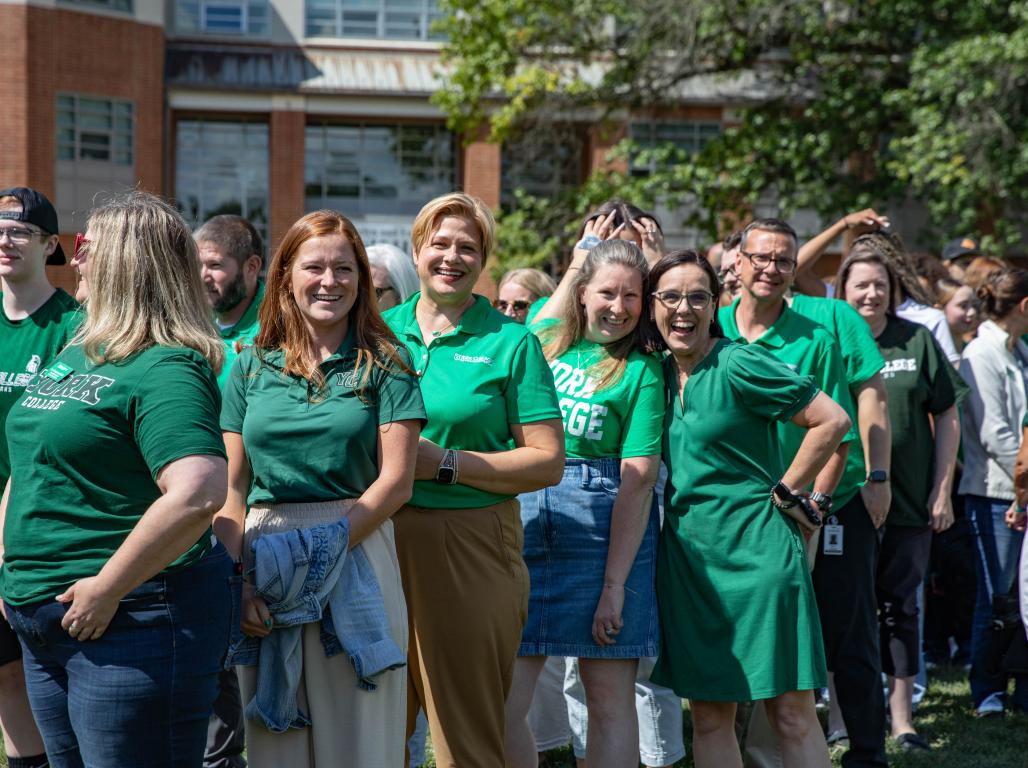 York College employees and community members wearing green gather outside on campus for National College Colors Day.
