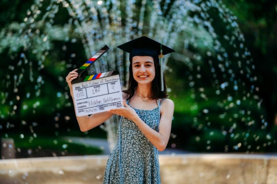 Ashely Hettleman poses with an open movie film clapboard. 