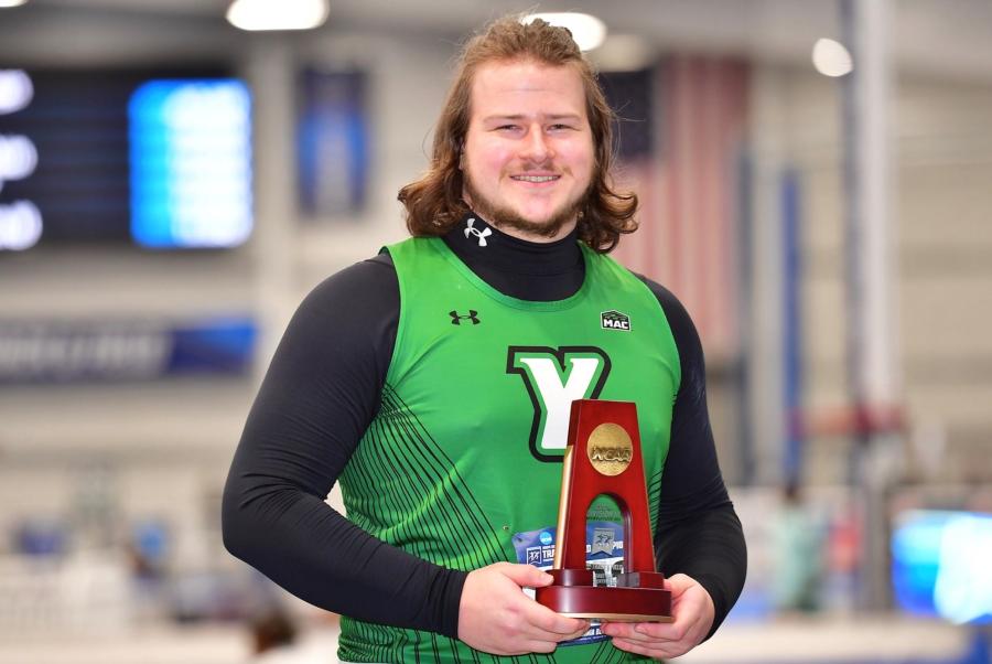Andrew Mott in his York College Wrestling uniform holds his All-American trophy for seventh place in the 2024 NCAA Division III Indoor Track and Field Championships.