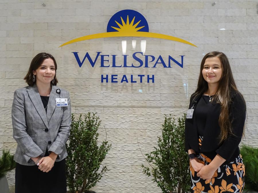 Rachel Rambler and Erica Rinehart pose for a photo in front of a WellSpan Health sign.