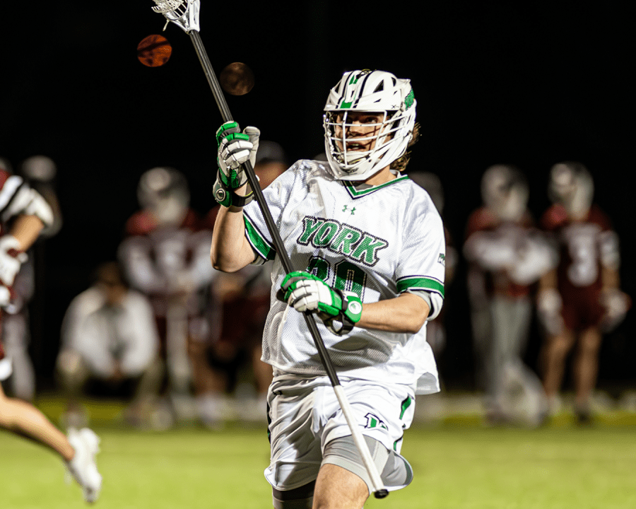 York College Men's Lacrosse player running on the field at night.