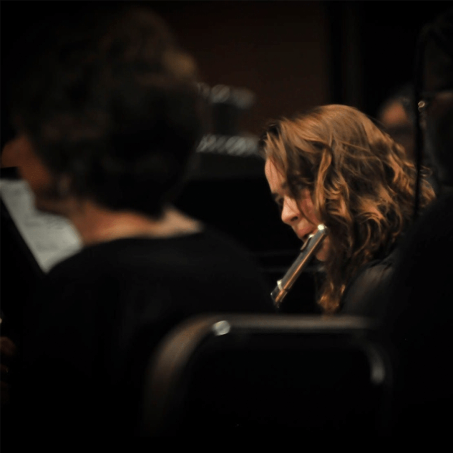 An individual playing the flute in an ensemble setting.