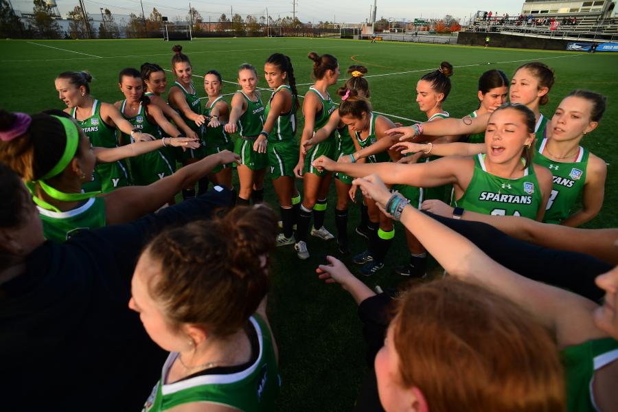 A group of field hockey players in a team huddle.
